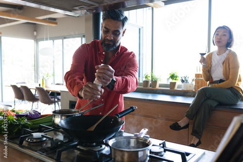Happy diverse couple preparing dinner together, cooking in kitchen