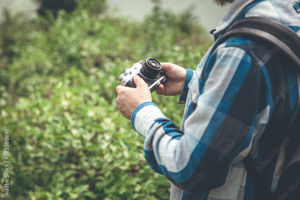 Fototapeta premium Vintage film camera in male hands on a hike in nature.