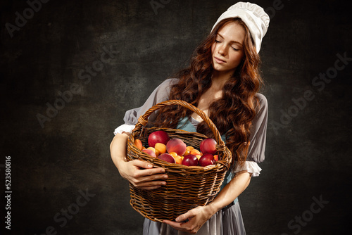 Portrait of charming redhair girl with long curly hair like girl of renaissance eras, lady-peasant isolated on dark background. Eras comparison, beauty, art,