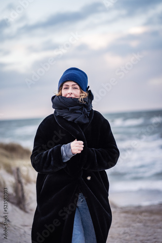 woman walks towards the camera at a cold windy evening at the German North Sea 