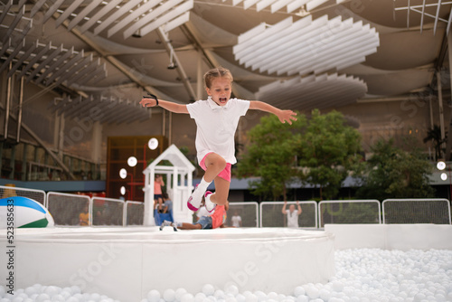 Happy little girl playing white plastic balls pool in amusement park. playground for kids. photo