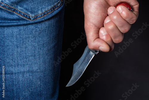 Man holding a knife in a threatening stance ready to fight photo