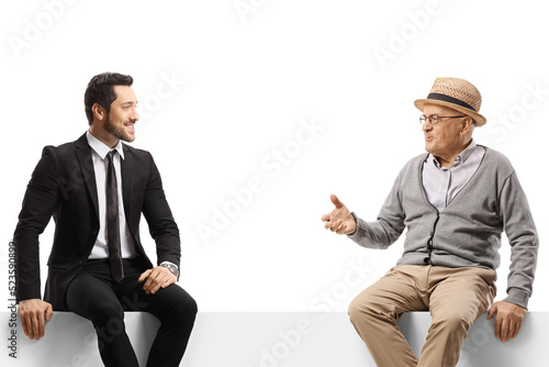 Elderly man and a young businessman sitting on a panel and talking