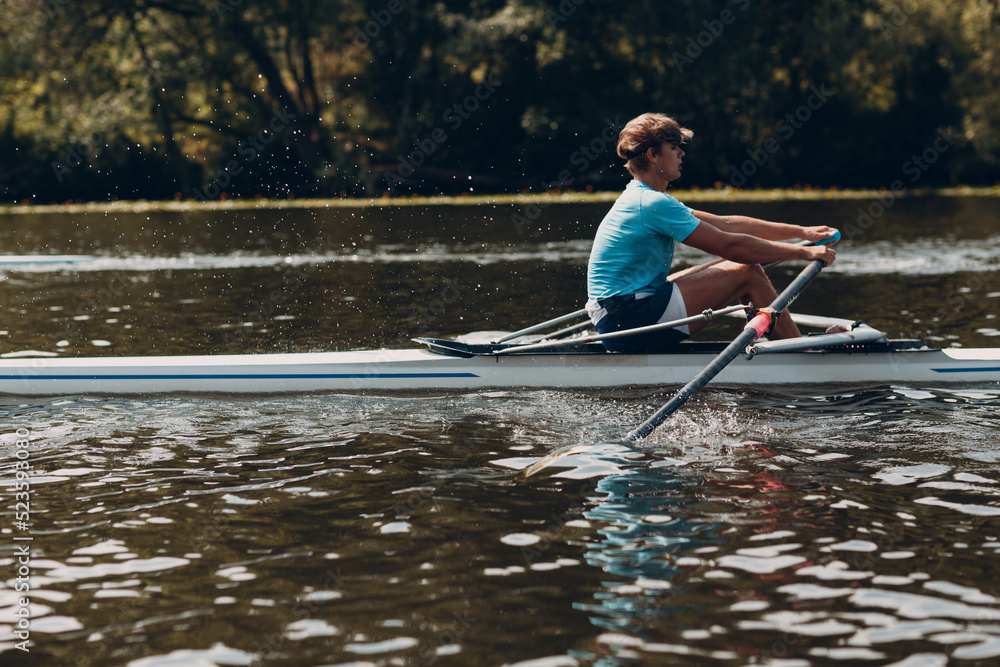 Sportsman single scull man rower rowing on boat.