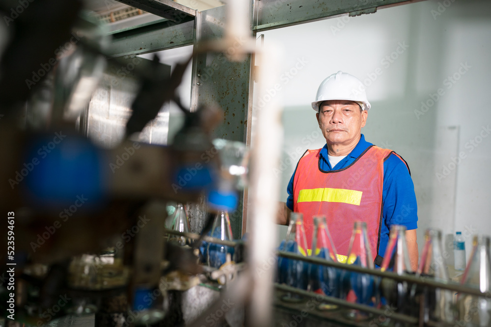 worker controlling the work of machine in production line at beverage industry.