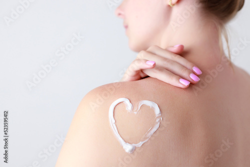 female shoulder with heart shaped cream. skin care