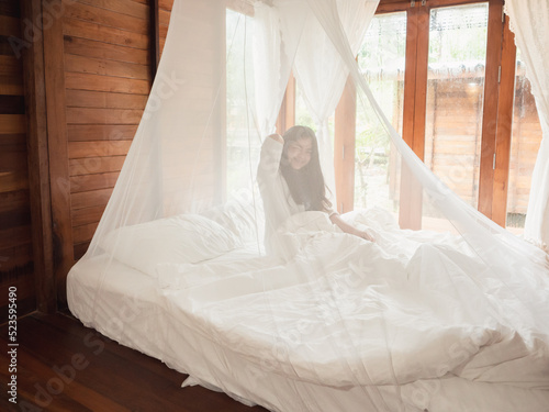 Woman stretching in bed after wake up, Happy greets new day with warm sunlight.