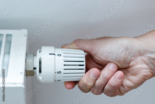 Close Up Of Hand Adjusting Heating Thermostat