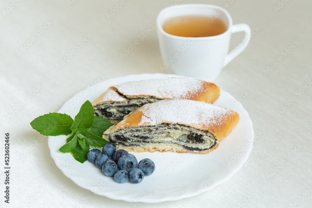 There is a plate of poppy seed cake on the table and a cup of tea next to it.