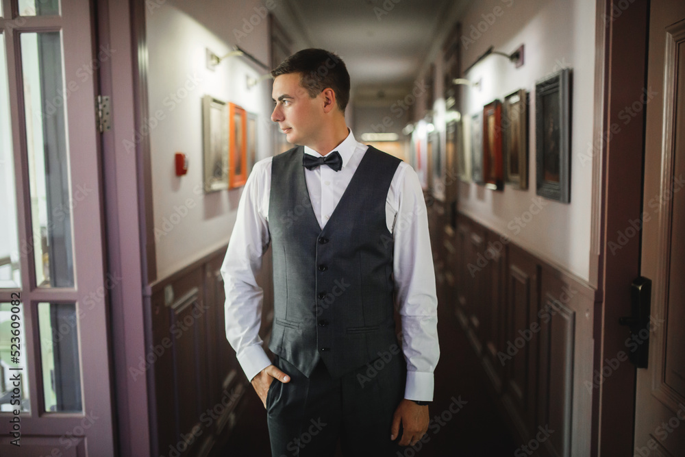 Fototapeta premium groom at wedding tuxedo smiling and waiting for bride. Rich groom at wedding day. Elegant groom in costume and bow-tie.