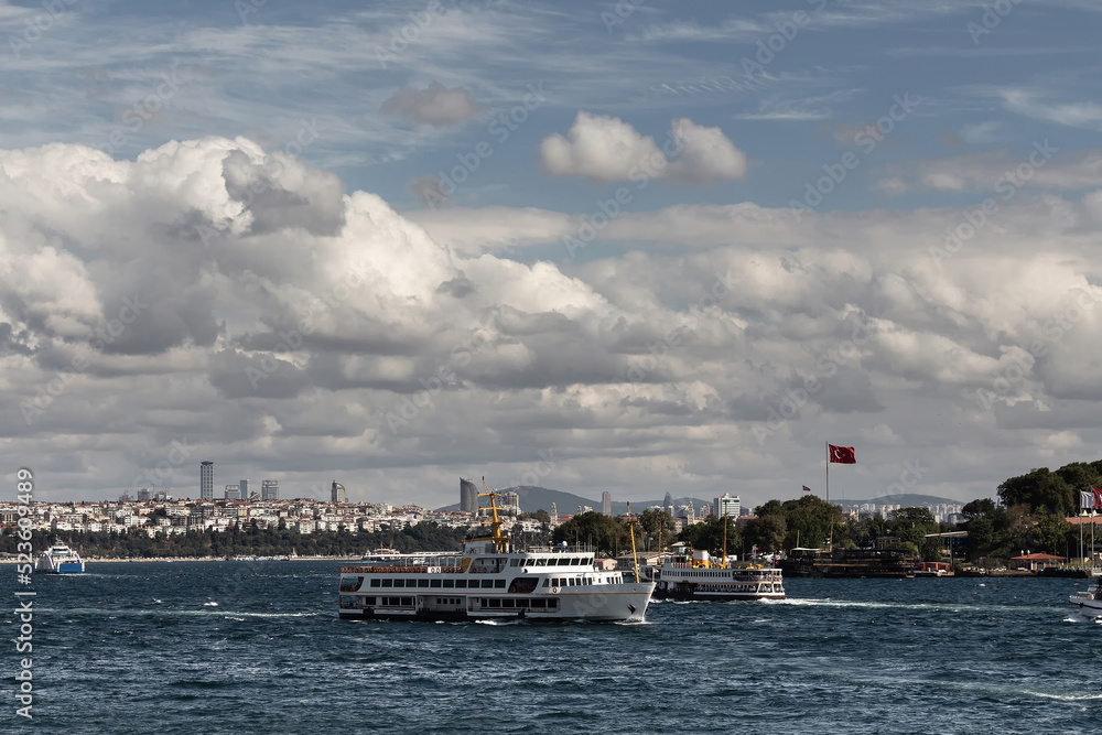 View of ferryboats passing in front of Topkapi Palace in Istanbul. Asian side is in the background. It is a sunny summer day.