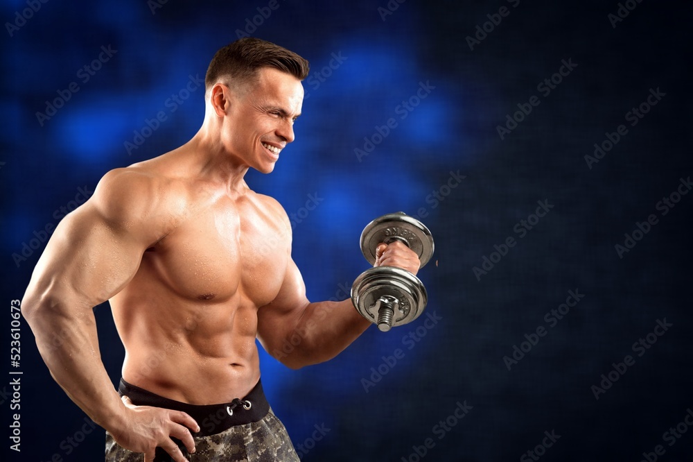 Brutal sweaty strong young man athlete with naked body standing doing workout with dumbbels and showing strong pumped up biceps. Sport men body concept.
