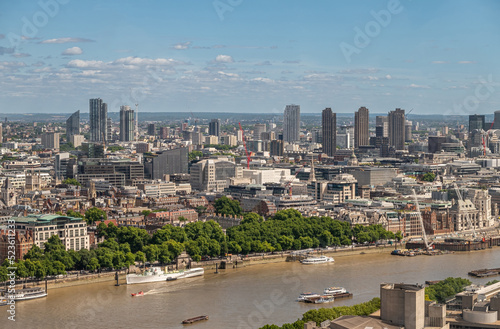London, UK - July 4, 2022: Seen from London Eye. Along Brown Thames river, Victoria Embankment from its gardens to Blackfriars bridge. Urban jungle cityscape behind under blue cloudscape.
