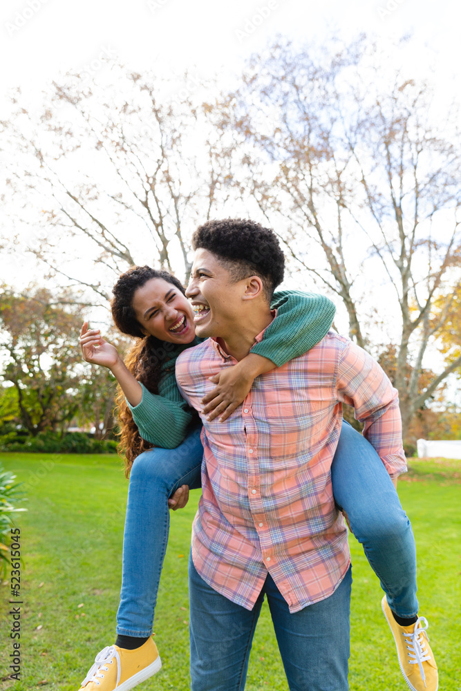 Happy biracial couple having fun piggybacking in garden and laughing Happy biracial couple having fun piggybacking in garden and laughing