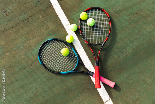 Detail of two tennis rackets and tennis balls lying on the ground at an outdoor tennis court