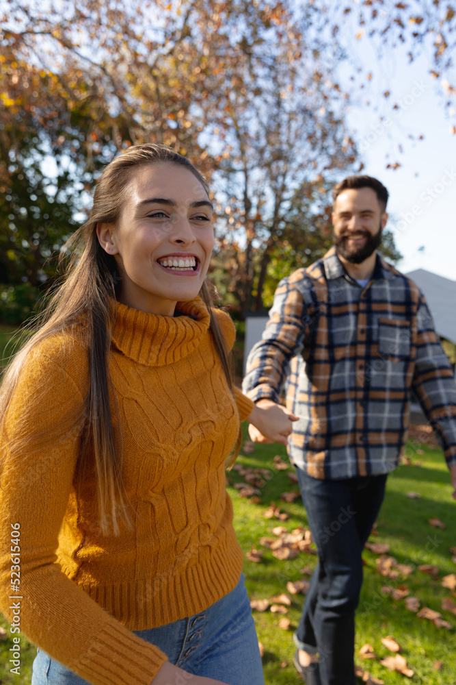 Vertical image of happy caucasian couple walking in autumn garden