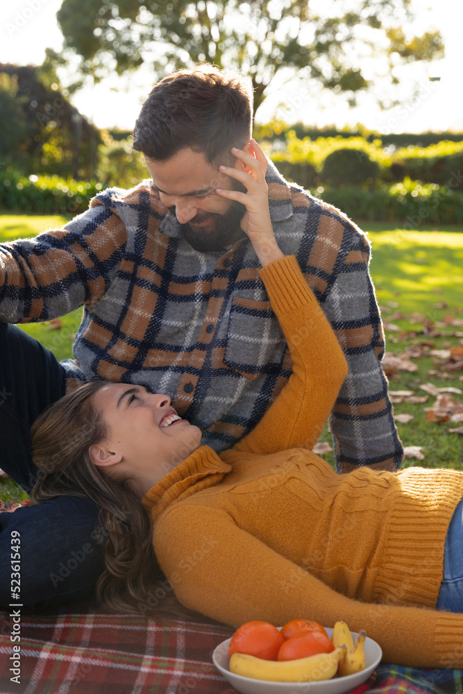 Fototapeta premium Romantic caucasian couple on rug having picnic and embracing in sunny autumn garden
