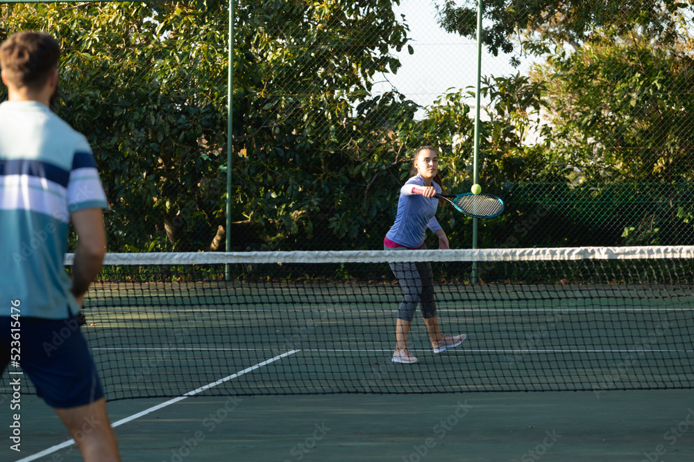 Caucasian couple playing tennis on outdoor tennis court