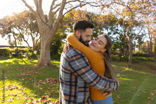 Happy caucasian couple smiling and hugging in sunny autumn garden