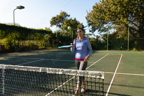 Caucasian woman playing tennis bouncing ball on racket on outdoor tennis court
