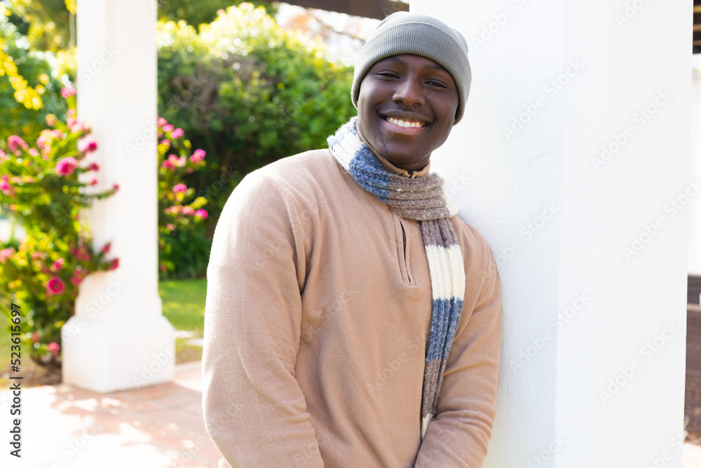 Portraif of smiling african american man at home sitting in garden wearing hat and scarf Portraif of smiling african american man at home sitting in garden wearing hat and scarf