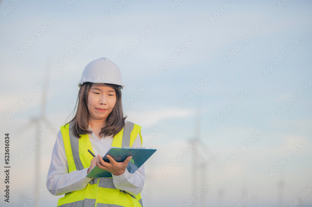 women engineer working and holding the report at wind turbine farm Power Generator Station on mountain,Thailand people women engineer working and holding the report at wind turbine farm Power Generator Station on mountain,Thailand people