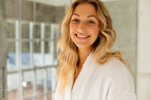 Portrait of happy caucasian woman wearing robe  smiling in bathroom