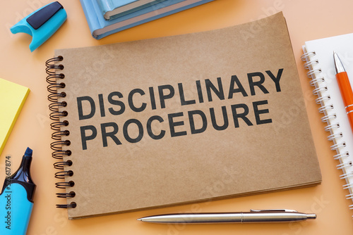 Notebook about disciplinary procedure with papers on the table.