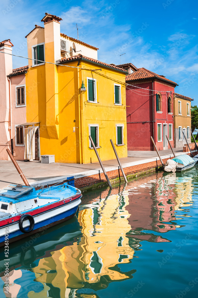Yellow and red houses on the canal in Burano island, Venice, Italy.