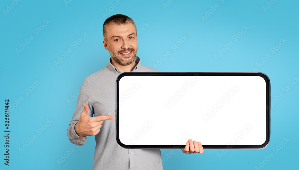 Cheerful Man Holding Large Smartphone With Empty Screen, Blue Background Cheerful Man Holding Large Smartphone With Empty Screen, Blue Background