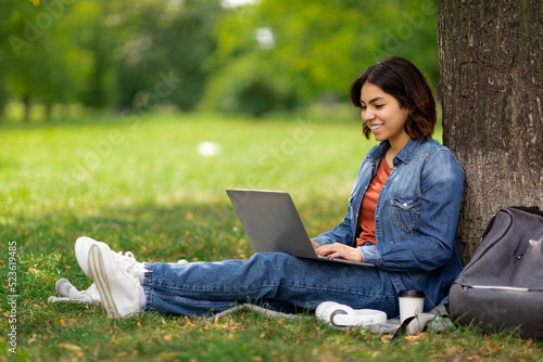 E-learning Concept. Arab Female Student With Laptop Sitting Under Tree In Park