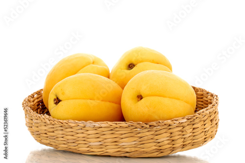 Several bright yellow juicy pineapple apricots in a straw bowl, macro isolated on a white background.