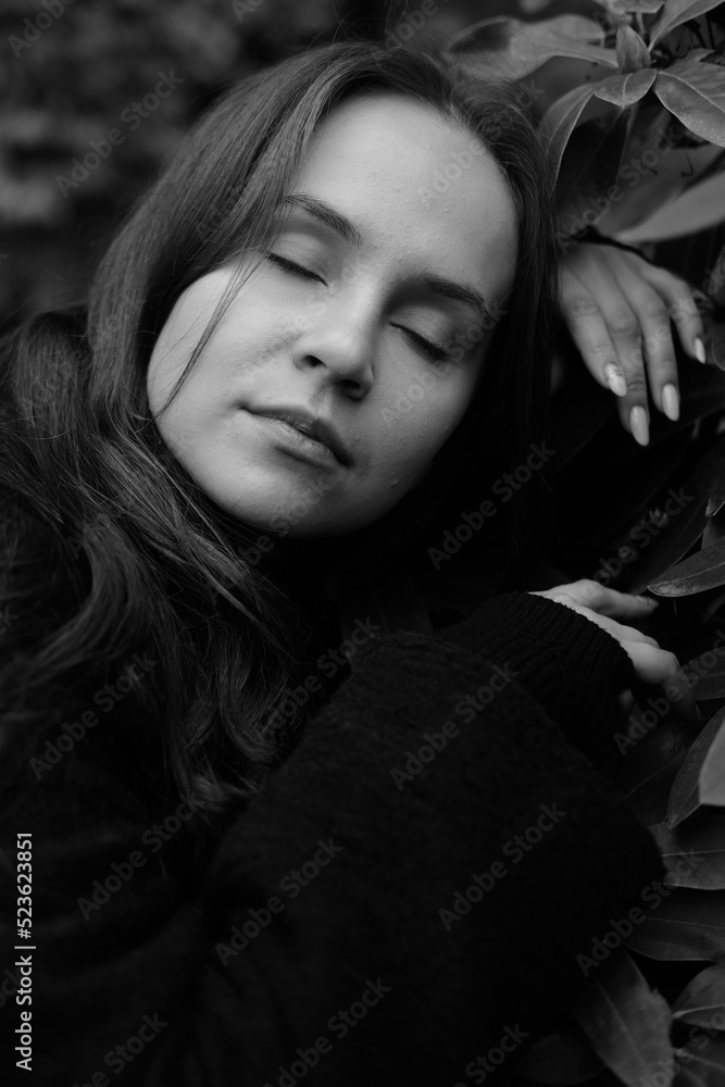 Brunette girl with closed eyes on the background of plantleaves Brunette girl with closed eyes on the background of plantleaves