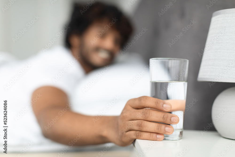 Selective focus on glass of water by eastern guy bed Selective focus on glass of water by eastern guy bed