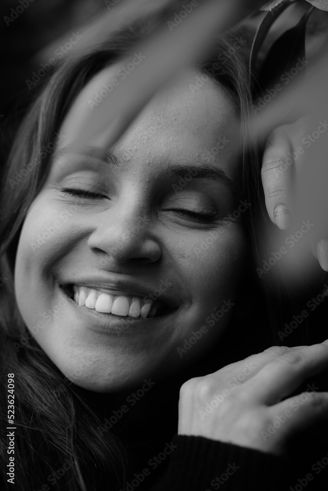Fototapeta premium Brunette girl with closed eyes on the background of plantleaves