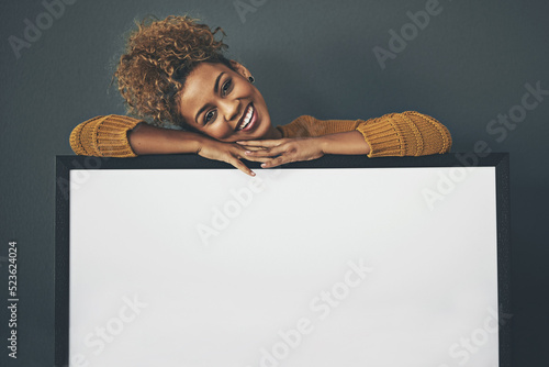 Fototapeta Woman standing with blank sign or portrait frame, showing copy space for advertising or marketing on dark background