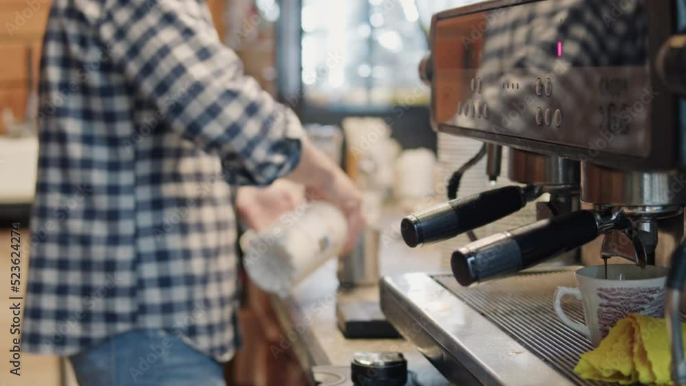 Selective focus on male barista, standing behind counter of cafe, preparing coffee at counter coffee shop, heating fresh milk for making cappuccino or latte coffee hot drink Selective focus on male barista, standing behind counter of cafe, preparing coffee at counter coffee shop, heating fresh milk for making cappuccino or latte coffee hot drink