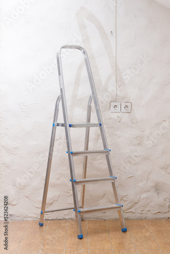 A simple stepladder stands on the floor in an empty home room.