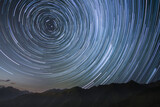 silhouetted mountains with circumpolar star trails in northern sky