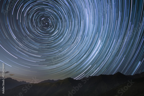 silhouetted mountains with circumpolar star trails in northern sky photo
