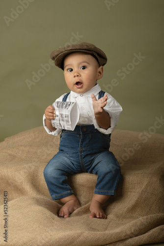 Cute funny baby dressed up like a newsboy holding a newspaper 