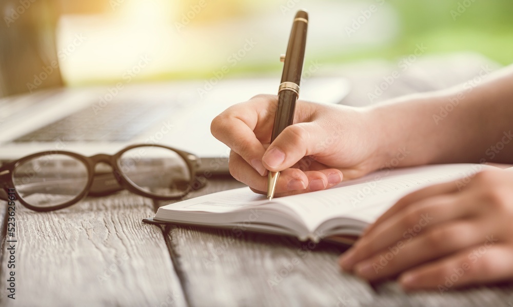 Student preparing for college test, exam, reading book, studying textbook, writing notes. Learning workplace table, hands with pen Student preparing for college test, exam, reading book, studying textbook, writing notes. Learning workplace table, hands with pen