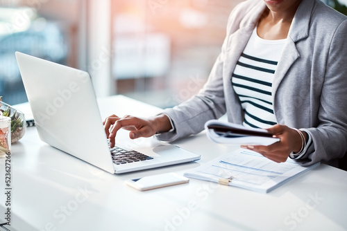Business woman typing on laptop, reading from notebook and planning a strategy in an office at work. Corporate employee, manager or boss sending emails, completing a proposal and browsing internet