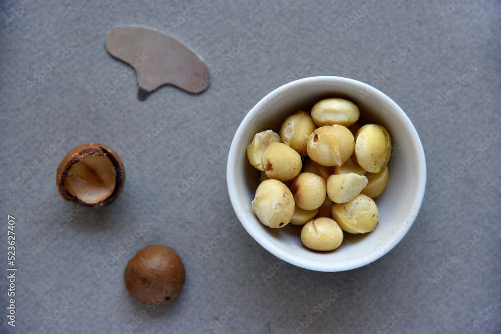 Delicious peeled Macadamia nut in a salad bowl on a gray background. The kernels of a delicious Macadamia nut close-up. Delicious peeled Macadamia nut in a salad bowl on a gray background. The kernels of a delicious Macadamia nut close-up.