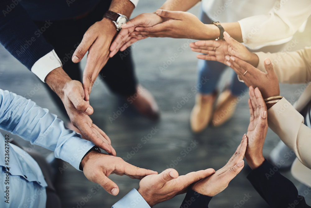 Circle of hands, teamwork and togetherness with a group of business colleagues standing in a team huddle from above. Working together, showing unity and giving support in a meeting for motivation