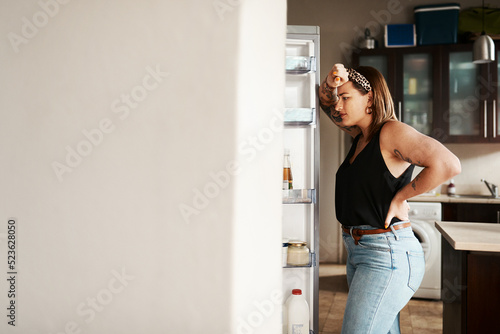 Obraz na plátně Plus size, chubby and hungry woman looking in a fridge, thinking of food or searching for meal while on a diet