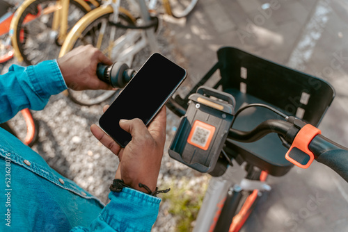 Top view of hand with smartphone over bicycle