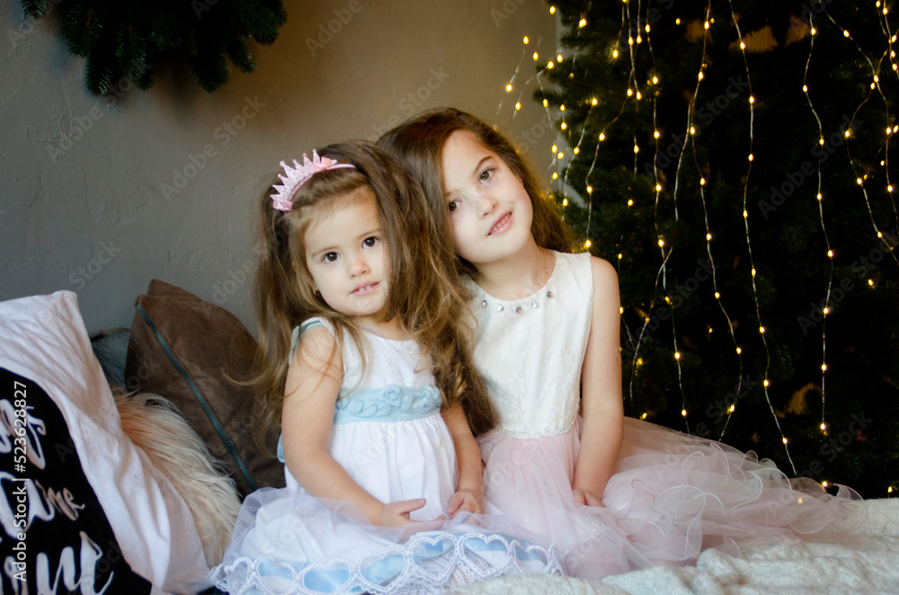 two little girls in a christmas dress near decorated new year tree two little girls in a christmas dress near decorated new year tree