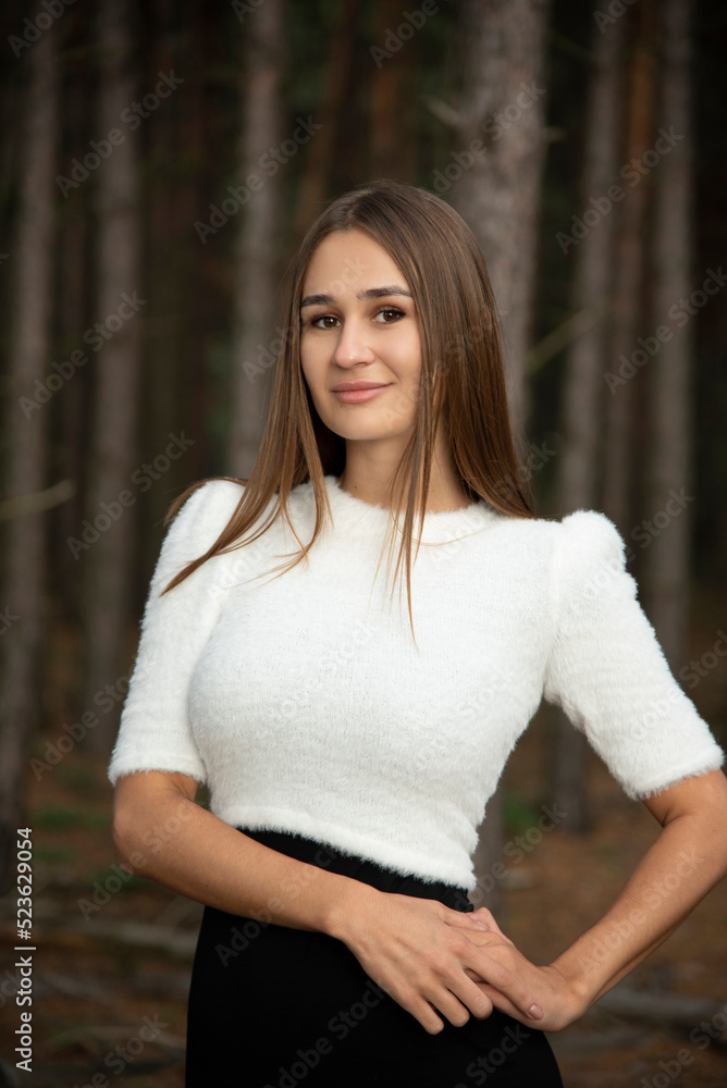 portrait of brunette woman in forest in white and black dress