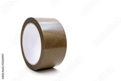 A roll of brown adhesive tape on a white background in the center of the image. A stationery item in the form of sticky tape for gluing paper or for a delivery service. Free space for text